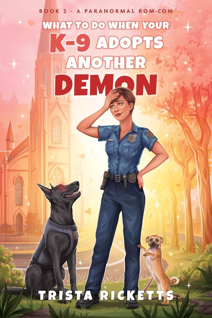 Book cover for 'What to Do When Your K-9 Adopts Another Demon' featuring a female police officer with short brown hair and a blue uniform, standing with a black K-9 dog and a smaller dog. The background shows a colorful park scene with trees and a church.
